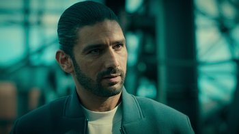 Movie still from “Ganglands” (2021), created by Julien Leclercq – A person wearing a jacket; Close Up shot, Over the shoulder angle