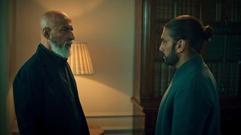 Movie still from “Ganglands” (2021), created by Julien Leclercq – Two men standing next to each other in a room; Medium shot, Over the shoulder angle