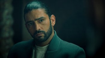 Movie still from “Ganglands” (2021), created by Julien Leclercq – A person wearing a jacket; Close Up shot, Over the shoulder angle