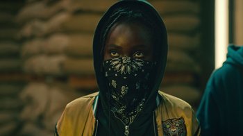 Movie still from “Ganglands” (2021), created by Julien Leclercq – A person wearing a mask and a yellow jacket; Close Up shot, Low angle