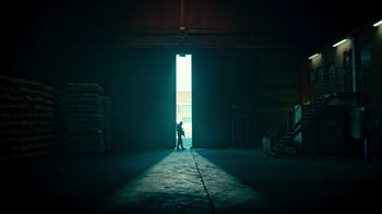 Movie still from “Ganglands” (2021), created by Julien Leclercq – A man standing in a dark room in front of an open door; Extreme Wide shot, Low angle