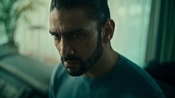 Movie still from “Ganglands” (2021), created by Julien Leclercq – A person wearing a green shirt; Close Up shot, Low angle