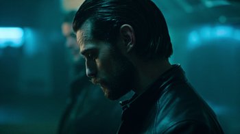 Movie still from “Ganglands” (2021), created by Julien Leclercq – A person wearing a leather jacket; Close Up shot, Over the shoulder angle