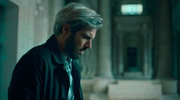 Movie still from “Ganglands” (2021), created by Julien Leclercq – A man in a suit and tie looking to his left; Close Up shot, Over the shoulder angle