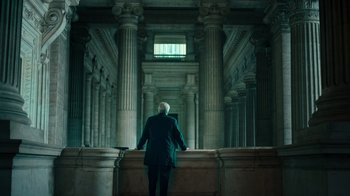 Movie still from “Ganglands” (2021), created by Julien Leclercq – A man standing in front of a window in a building; Wide shot, Low angle
