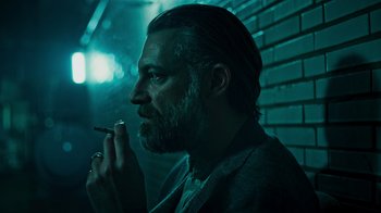Movie still from “Ganglands” (2021), created by Julien Leclercq – A man smoking a cigarette while wearing a suit; Close Up shot, Low angle