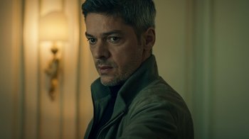 Movie still from “Ganglands” (2021), created by Julien Leclercq – A person wearing a suit and tie; Close Up shot, Low angle