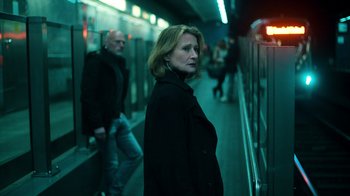 Movie still from “Ganglands” (2021), created by Julien Leclercq – A woman standing in front of a subway train platform; Medium shot, Over the shoulder angle