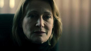 Movie still from “Ganglands” (2021), created by Julien Leclercq – A woman's face in a dark room; Close Up shot, Low angle