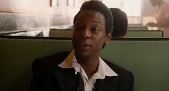Movie still from “Get on Up” (2014), directed by Tate Taylor – A man sitting on a bench wearing a suit and white shirt; Close Up shot, Over the shoulder angle