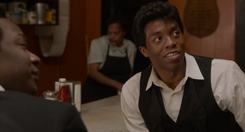 Movie still from “Get on Up” (2014), directed by Tate Taylor – A man sitting at a table in front of a woman; Close Up shot, Over the shoulder angle