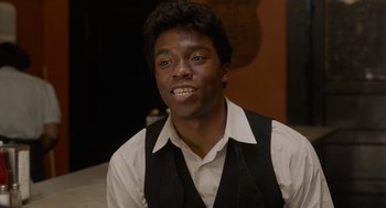Movie still from “Get on Up” (2014), directed by Tate Taylor – A young man in a vest and tie; Close Up shot, Over the shoulder angle