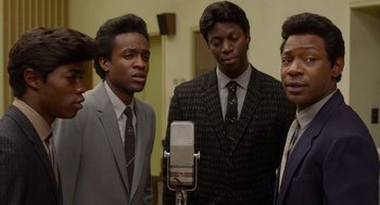 Movie still from “Get on Up” (2014), directed by Tate Taylor – A group of men standing next to each other in front of a microphone; Medium shot, High angle