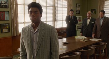 Movie still from “Get on Up” (2014), directed by Tate Taylor – A man standing in front of two other men in a room; Medium shot, Over the shoulder angle