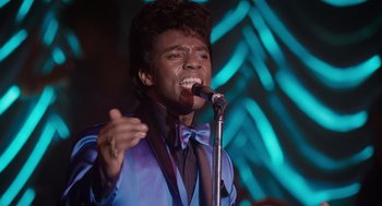 Movie still from “Get on Up” (2014), directed by Tate Taylor – A man in a blue jacket is singing into a microphone; Close Up shot, Low angle