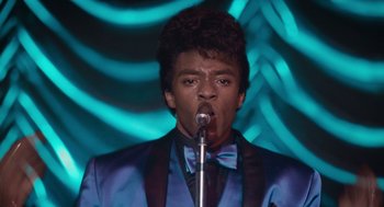 Movie still from “Get on Up” (2014), directed by Tate Taylor – A man in a blue jacket and bow tie is singing; Close Up shot, Low angle