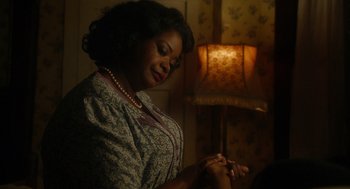 Movie still from “Get on Up” (2014), directed by Tate Taylor – An african american woman sitting in a dimly - lit room; Close Up shot, Over the shoulder angle