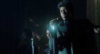 Movie still from “Get on Up” (2014), directed by Tate Taylor – A man standing next to a microphone in a dark room; Close Up shot, Low angle
