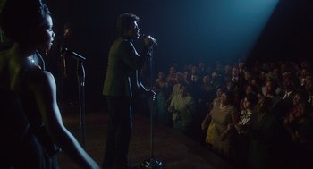 Movie still from “Get on Up” (2014), directed by Tate Taylor – A person on a stage singing into a microphone; Wide shot, Low angle