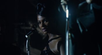 Movie still from “Get on Up” (2014), directed by Tate Taylor – A woman standing in front of a microphone in a dark room; Close Up shot, Over the shoulder angle
