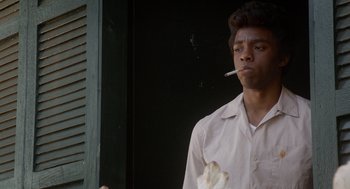 Movie still from “Get on Up” (2014), directed by Tate Taylor – A man smoking a cigarette while standing in front of a window; Close Up shot, Over the shoulder angle