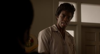 Movie still from “Get on Up” (2014), directed by Tate Taylor – A man standing in front of a plate of food in front of a window; Close Up shot, Over the shoulder angle