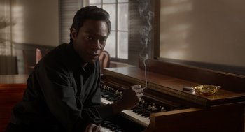 Movie still from “Get on Up” (2014), directed by Tate Taylor – A man sitting in front of an organ with smoke coming out of his mouth; Close Up shot, High angle