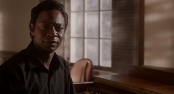 Movie still from “Get on Up” (2014), directed by Tate Taylor – A man sitting in front of a window in a room; Close Up shot, Over the shoulder angle