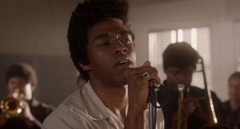 Movie still from “Get on Up” (2014), directed by Tate Taylor – A man is singing into a microphone in front of a group; Close Up shot, Low angle