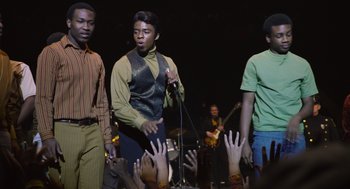 Movie still from “Get on Up” (2014), directed by Tate Taylor – A group of men standing next to each other on a stage; Medium shot, Low angle