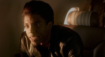 Movie still from “Get on Up” (2014), directed by Tate Taylor – A young man sitting in a chair in the dark; Close Up shot, Over the shoulder angle