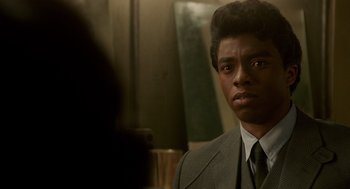 Movie still from “Get on Up” (2014), directed by Tate Taylor – A man wearing a suit and tie looking to his left; Close Up shot, Over the shoulder angle