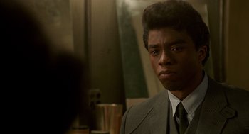Movie still from “Get on Up” (2014), directed by Tate Taylor – A man wearing a suit and tie in front of a mirror; Close Up shot, Over the shoulder angle
