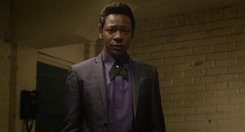 Movie still from “Get on Up” (2014), directed by Tate Taylor – A man in a suit and purple shirt standing next to a brick wall; Close Up shot, Low angle