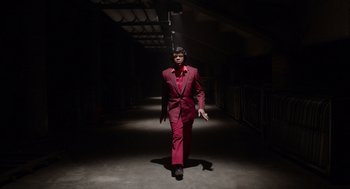 Movie still from “Get on Up” (2014), directed by Tate Taylor – A man in a red suit walking down a dark hallway; Wide shot, Low angle