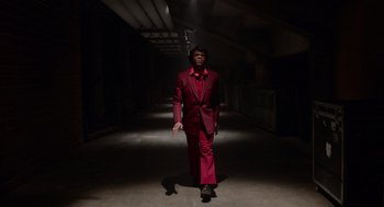 Movie still from “Get on Up” (2014), directed by Tate Taylor – A man in a red suit walking down a hallway; Wide shot, Low angle