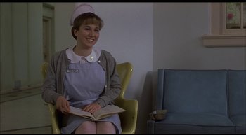Movie still from “Girl, Interrupted” (1999), directed by James Mangold – A woman sitting in a chair holding an open book; Medium shot, Low angle