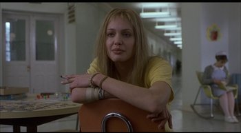 Movie still from “Girl, Interrupted” (1999), directed by James Mangold – A woman sitting on a chair with her arms crossed; Medium shot, Over the shoulder angle