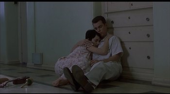 Movie still from “Girl, Interrupted” (1999), directed by James Mangold – A man and a woman sitting on the ground hugging; Medium shot, High angle