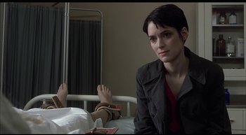Movie still from “Girl, Interrupted” (1999), directed by James Mangold – A woman sitting on a hospital bed next to a patient; Medium shot, Over the shoulder angle
