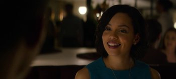 Movie still from “Black Mirror” (2011), created by Charlie Brooker – A woman smiling at the camera in front of a group of people; Close Up shot, Over the shoulder angle