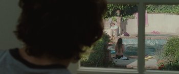 Movie still from “Greenberg” (2010), directed by Noah Baumbach – Two people sitting in a backyard looking out a window; Wide shot, Over the shoulder angle