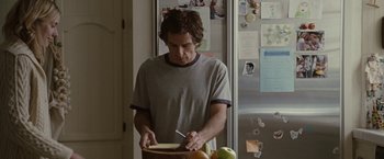 Movie still from “Greenberg” (2010), directed by Noah Baumbach – A man cutting a piece of paper in a kitchen; Medium shot, Over the shoulder angle