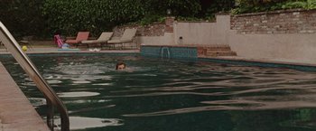 Movie still from “Greenberg” (2010), directed by Noah Baumbach – A man swimming in a pool near a brick wall; Extreme Wide shot, High angle