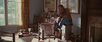 Movie still from “Greenberg” (2010), directed by Noah Baumbach – A man sitting on top of a chair in a living room; Wide shot, High angle