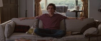 Movie still from “Greenberg” (2010), directed by Noah Baumbach – A man sitting on top of a couch in a living room; Medium shot, Over the shoulder angle