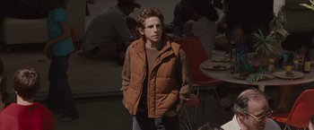 Movie still from “Greenberg” (2010), directed by Noah Baumbach – A man in a brown vest standing in front of a group of diners; Medium shot, Over the shoulder angle