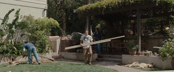 Movie still from “Greenberg” (2010), directed by Noah Baumbach – A man carrying a wooden board in a yard; Wide shot, Low angle