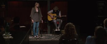 Movie still from “Greenberg” (2010), directed by Noah Baumbach – A man and a woman playing a song on a stage; Wide shot, Over the shoulder angle