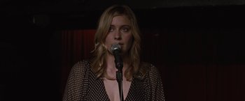 Movie still from “Greenberg” (2010), directed by Noah Baumbach – A woman standing in front of a microphone; Close Up shot, Over the shoulder angle